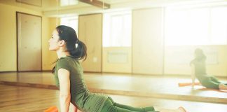 Woman practicing yoga on an orange mat in a bright studio