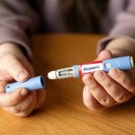 Ivermectin Craze: Defy the System or Fool’s Gold? Hands holding an Ozempic injection pen.