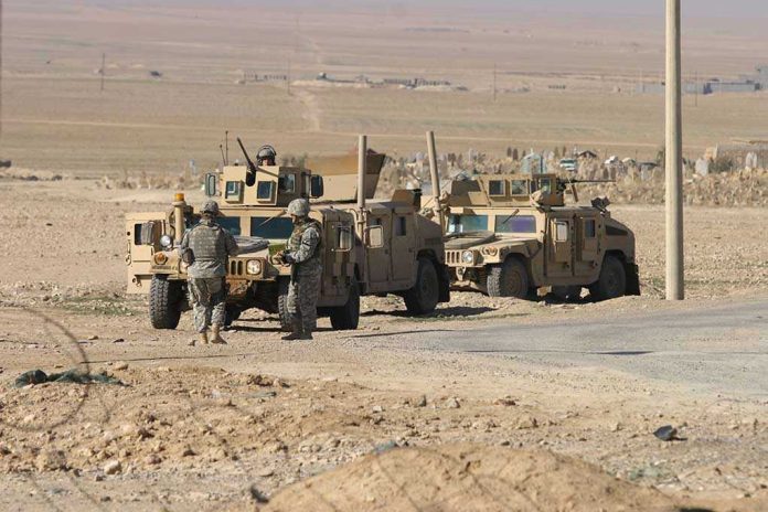 76580419 Soldiers standing near armored vehicles in desert terrain.