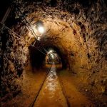 U.S. Gold Rush in Venezuela Unveiled Dimly lit underground tunnel with rail tracks and rocky walls