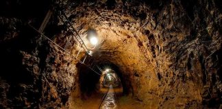 U.S. Gold Rush in Venezuela Unveiled Dimly lit underground tunnel with rail tracks and rocky walls