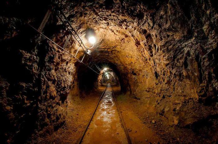 shutterstock_130135697 Dimly lit underground tunnel with rail tracks and rocky walls
