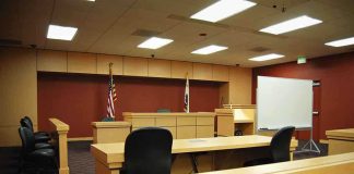 Judge’s Ruling Splits Mangione Case Wide Open Interior view of an empty courtroom with wooden furniture and American flags