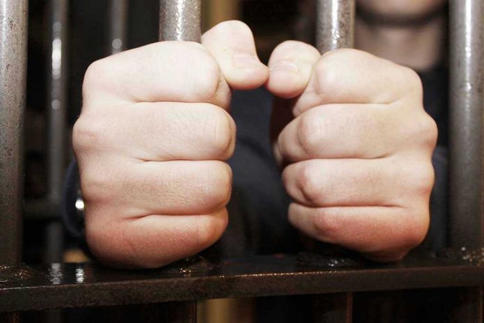Hands gripping jail cell bars tightly.