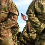 Army Base BLOODBATH — Cover-Up Fears IGNITE Soldiers stand in formation with American flag in background.