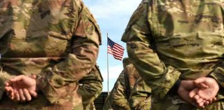 Army Base BLOODBATH — Cover-Up Fears IGNITE Soldiers stand in formation with American flag in background.