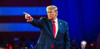 Trump’s LATEST PICK Sparks Firestorm — WHERE’S THE BEEF? Person in suit pointing during a public event.