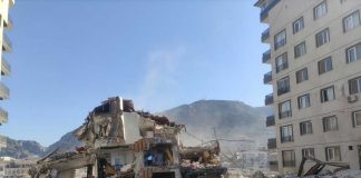 Collapsed building surrounded by debris and mountains