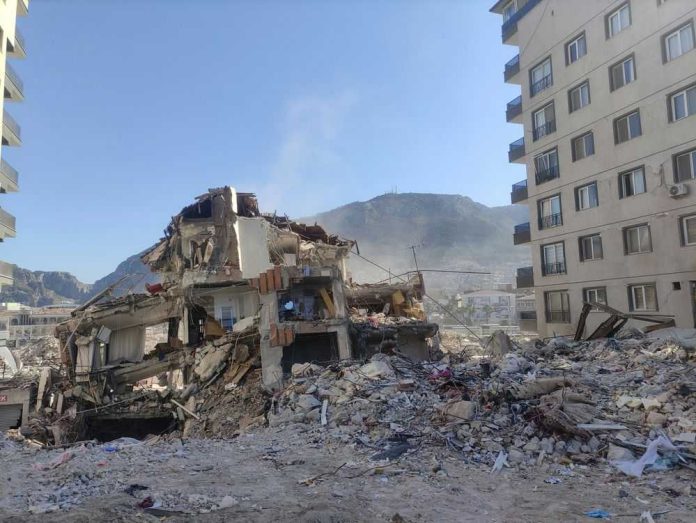2503713475-1 Collapsed building surrounded by debris and mountains