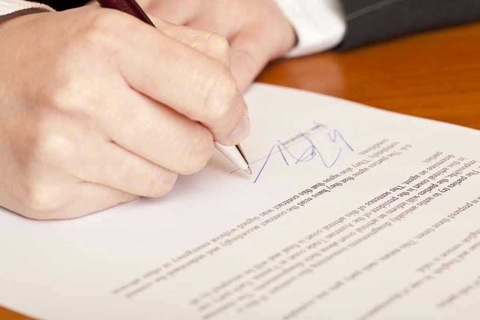 Hand signing a document with a pen.