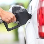 Oil Craters on PHANTOM Peace Deal — What This Means For You A hand holding a fuel nozzle while refueling a white vehicle at a gas station