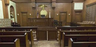 Historic First — HORRIFYING Fall FROM GRACE Interior view of an empty courtroom with wooden benches and a judges bench