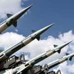 AI WAR BOX Hides In Ports — MISSLES in Plain Sight Array of military missiles against a blue sky with clouds