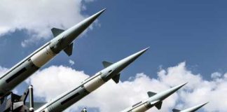Array of military missiles against a blue sky with clouds