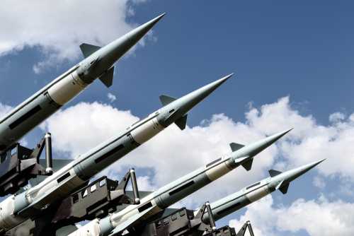 shutterstock_1235652937 Array of military missiles against a blue sky with clouds