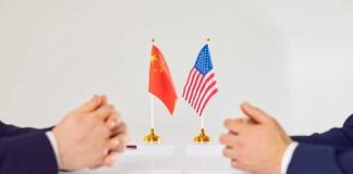 Trump’s NEW China Deal — Did He REALLY DO THAT? Two hands of individuals facing each other with flags of China and the USA on the table