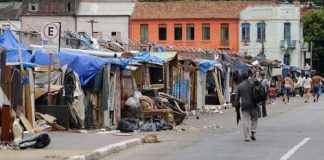 A street lined with makeshift shelters and a person walking by