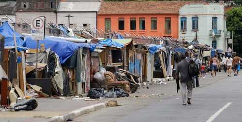 shutterstock_2302472543 A street lined with makeshift shelters and a person walking by