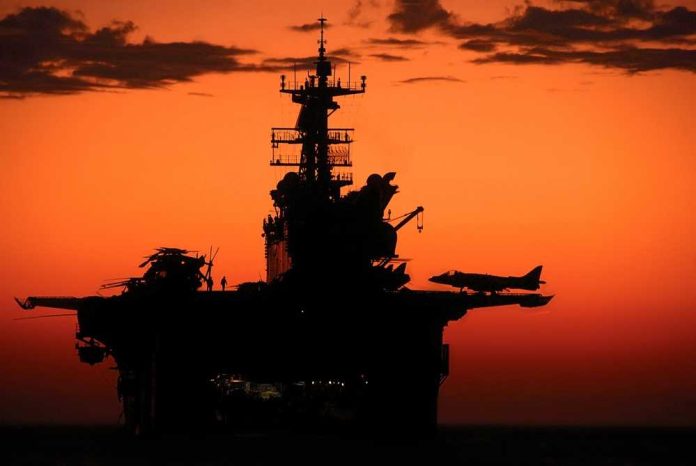 Silhouette of a naval aircraft carrier against a vibrant sunset