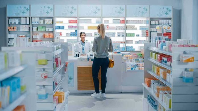 1952231947 Customer talking to pharmacist at a bright pharmacy.