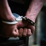 Hands in handcuffs behind back arrested person