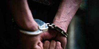 Hands in handcuffs behind back arrested person