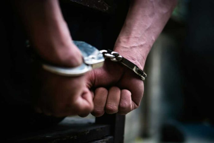 Hands in handcuffs behind back arrested person