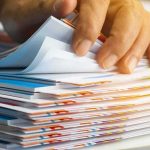 Files EXPLODE — Top EPSTEIN Recruiter Suddenly Dead Hand sorting through a stack of colorful documents