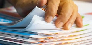 Files EXPLODE — Top EPSTEIN Recruiter Suddenly Dead Hand sorting through a stack of colorful documents