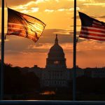 850,000 BLASTS, But What BROKE? Silhouetted American flags in front of the Capitol building during sunset