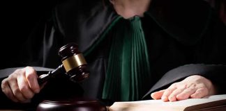 Judge in robe holding gavel beside open law book