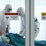 DEADLY OUTBREAK Surges — NO TREATMENT, NO VACCINE Healthcare workers in hazmat suits treat a patient in a quarantine room