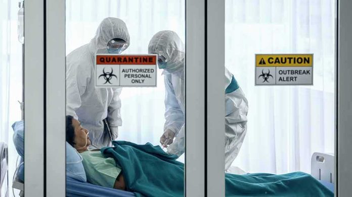 shutterstock_1647350797 Healthcare workers in hazmat suits treat a patient in a quarantine room