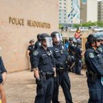 Mayor AXES Chief After DEADLY Chaos — NOT Nearly ENOUGH! Police officers in riot gear stand in formation outside a headquarters building