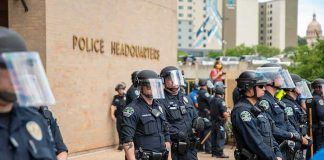 Mayor AXES Chief After DEADLY Chaos — NOT Nearly ENOUGH! Police officers in riot gear stand in formation outside a headquarters building
