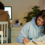 Middle Schoolers DRAFTED For ACTIVISM! Student in blue hoodie writing in notebook at desk