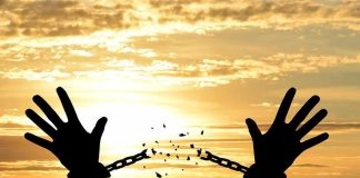 Silhouette hands breaking chains at sunset