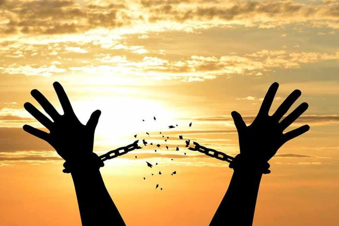 shutterstock_1019903881 Silhouette hands breaking chains at sunset