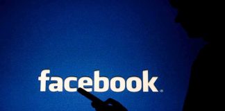 silhouette holding a smartphone in front of Facebook logo
