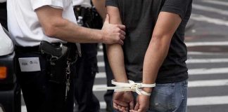 police officer detains person with hands zip-tied behind back