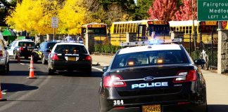 Police cars with lights on near school buses on a city street