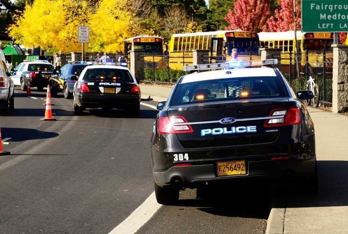 Police cars with lights on near school buses on a city street