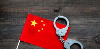 Chinese flag with metal handcuffs on wooden table