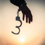 Child Killer WALKS — Totally FREE, No WATCHER! Hand with open handcuff in silhouette at sunset