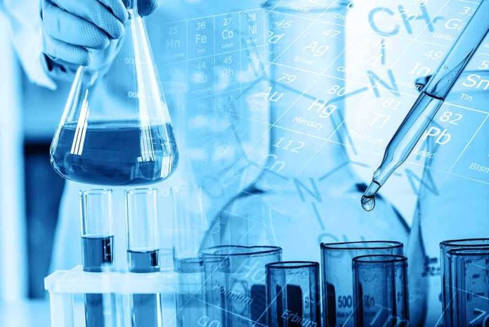 Scientist holding a flask with blue liquid and pipette over test tubes