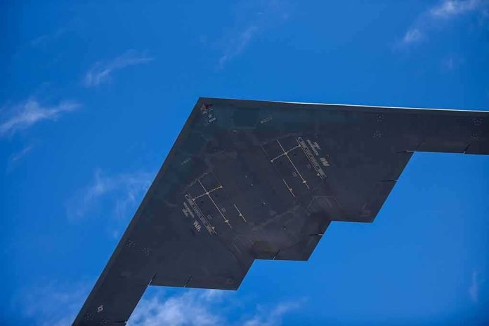 Stealth aircraft wing seen from below against blue sky