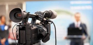 video camera filming a speaker at a podium