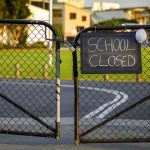 Chain-link school gate with a sign reading school closed