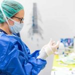 medical professional in blue gown putting on sterile gloves