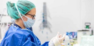 FIRST DEATHS Recorded — Now Can We Get ANSWERS??! medical professional in blue gown putting on sterile gloves